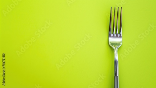 Single metal fork against bright green background photo