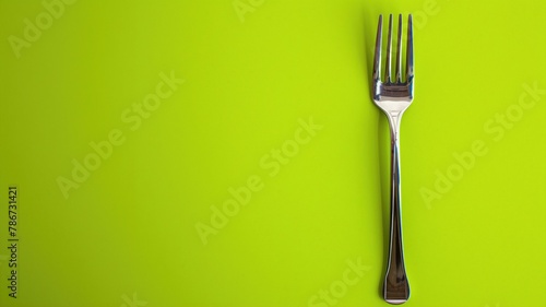 Single metallic fork on bright lime green background with ample negative space photo