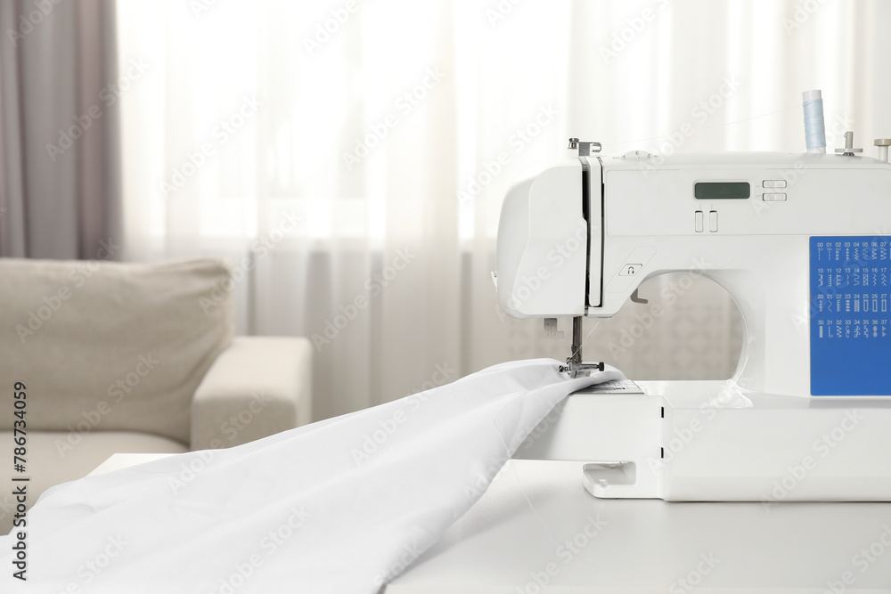 White sewing machine and fabric on table indoors, closeup