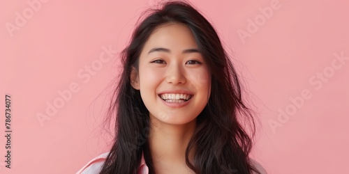 Radiant young Asian woman with a captivating smile and bob haircut against a soft pink background.