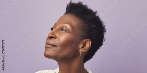 Relaxed middle-aged Black woman with closed eyes and natural curly hair, set against a lilac-colored wall. photo