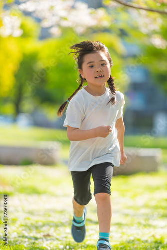芝生の公園を走る笑顔女の子