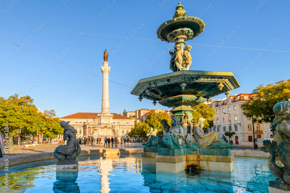 Fototapeta premium The monumental 19th century bronze fountain of four children with mermaids below, with the Column of Pedro IV behind, in Rossio Square, Lisbon, Portugal.