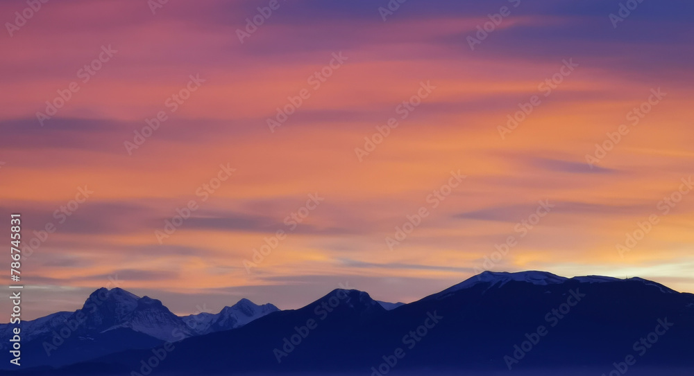 Obraz premium Tramonto luminoso viola arancio e rosa sopra le montagne innevate