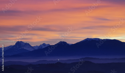 Tramonto luminoso viola arancio e rosa sopra le montagne innevate photo