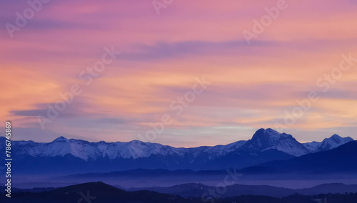 Tramonto luminoso viola arancio e rosa sopra le montagne innevate © GjGj