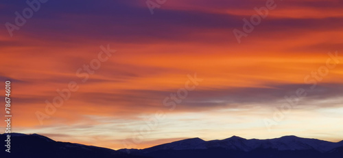 Nuvole rosse al tramonto sulla cime delle montagne photo