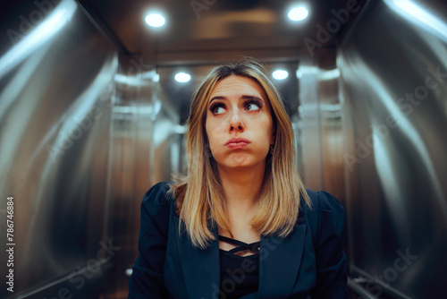 Anxious Office Worker Riding an Elevator at the Workplace. Stressed businesswoman feeling trapped into a broke lift
 photo
