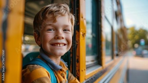 Image of a happy smiling school boy looking out the window of a school bus