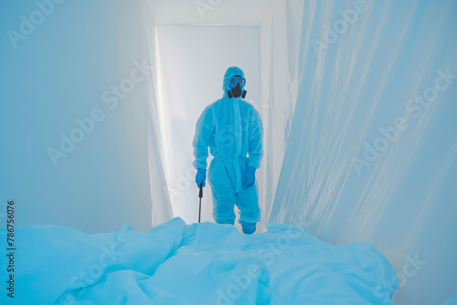 Faceless pest control worker in a protective suit sprays insect poison in a home
