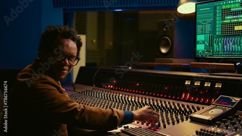 Bild auf Leinwand Portrait of african american sound designer mixing and mastering tracks with professional audio console in studio control room