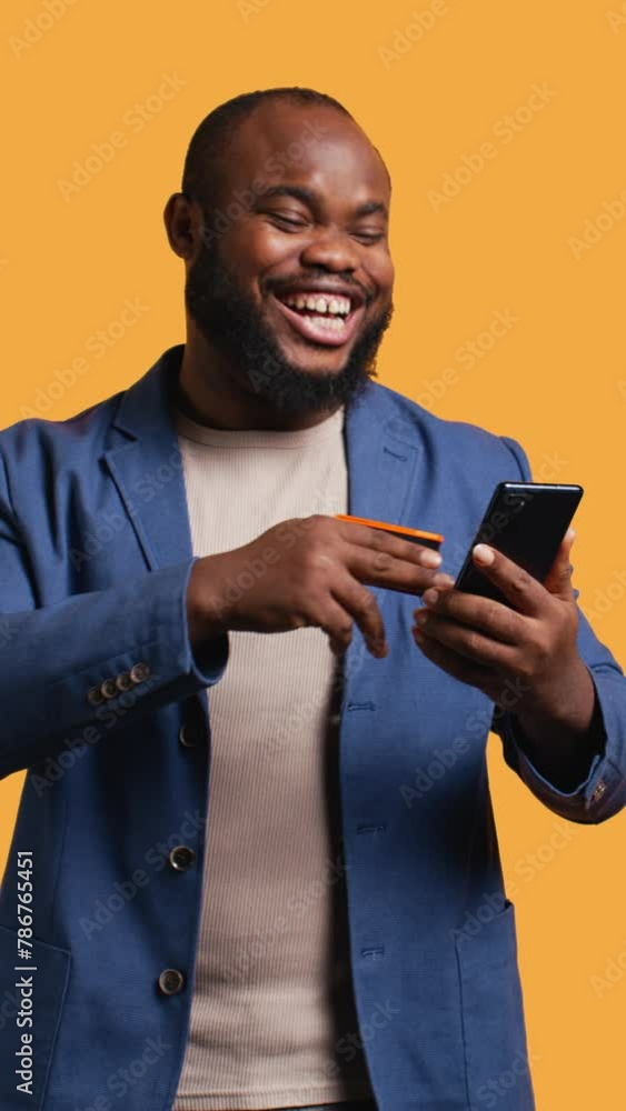 Vertical video Happy man adding payment method on phone website, delighted to take advantage of promotions, studio background. Person thrilled to do internet shopping, typing credit card data on Vertical video Happy man adding payment method on phone website, delighted to take advantage of promotions, studio background. Person thrilled to do internet shopping, typing credit card data on