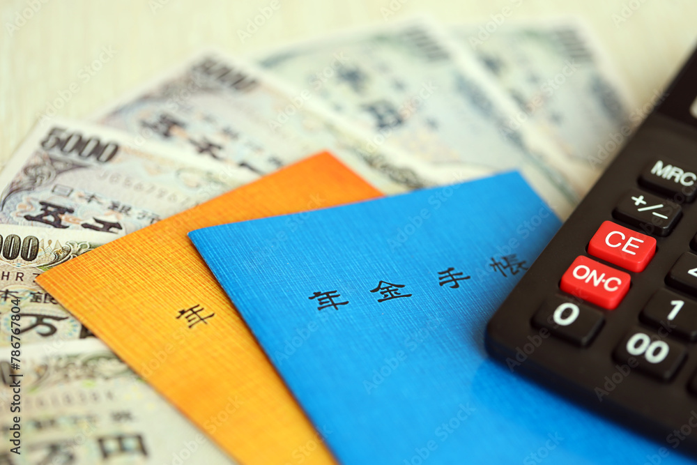 Japanese pension insurance booklets on table with yen money bills and calculator on table close up Japanese pension insurance booklets on table with yen money bills and calculator on table close up