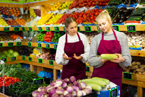 Obraz na plátně Female manager trains young part-time girl to recognize ripe and damaged zucchin