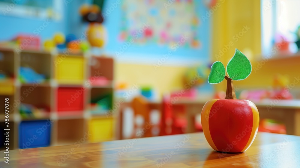 Toy apple with green leaves on table in colorful playroom