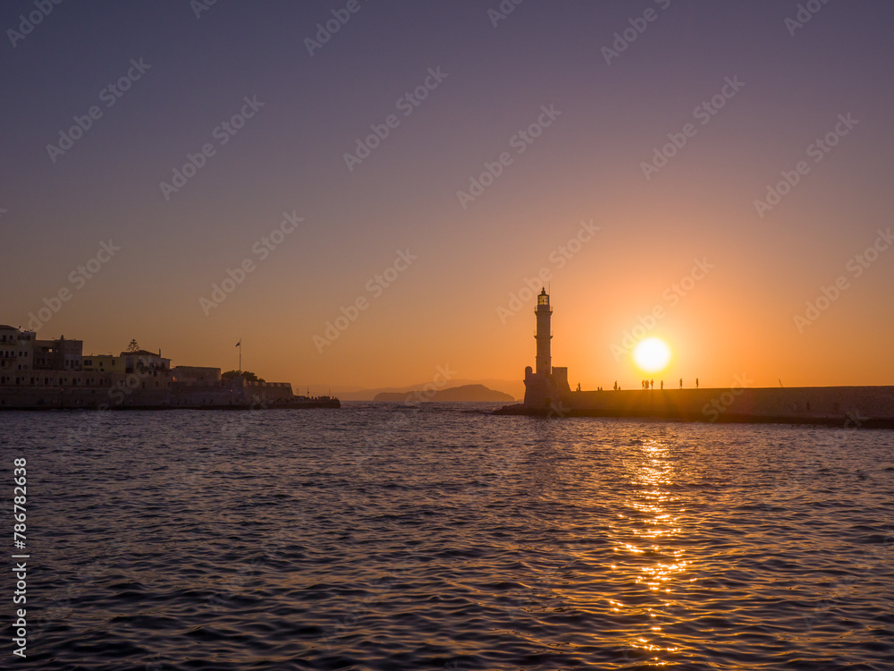 Old lighthouse in a port town at sunset (Chania, Crete, Greece)