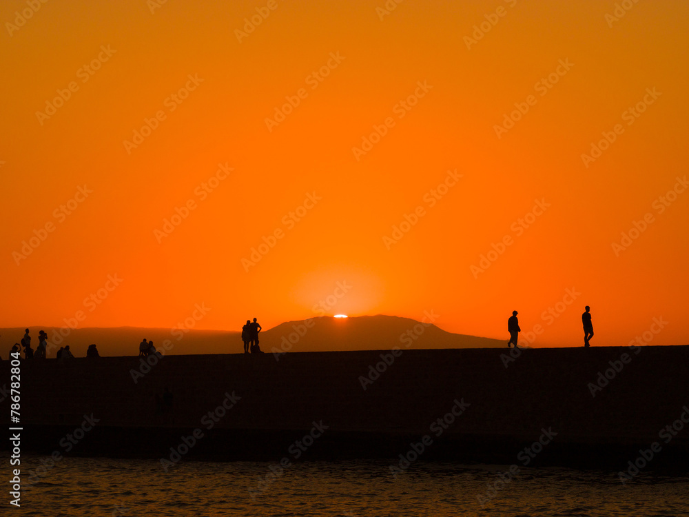 Fototapeta premium Silhouette of people in a port town at dusk (Chania, Crete, Greece)