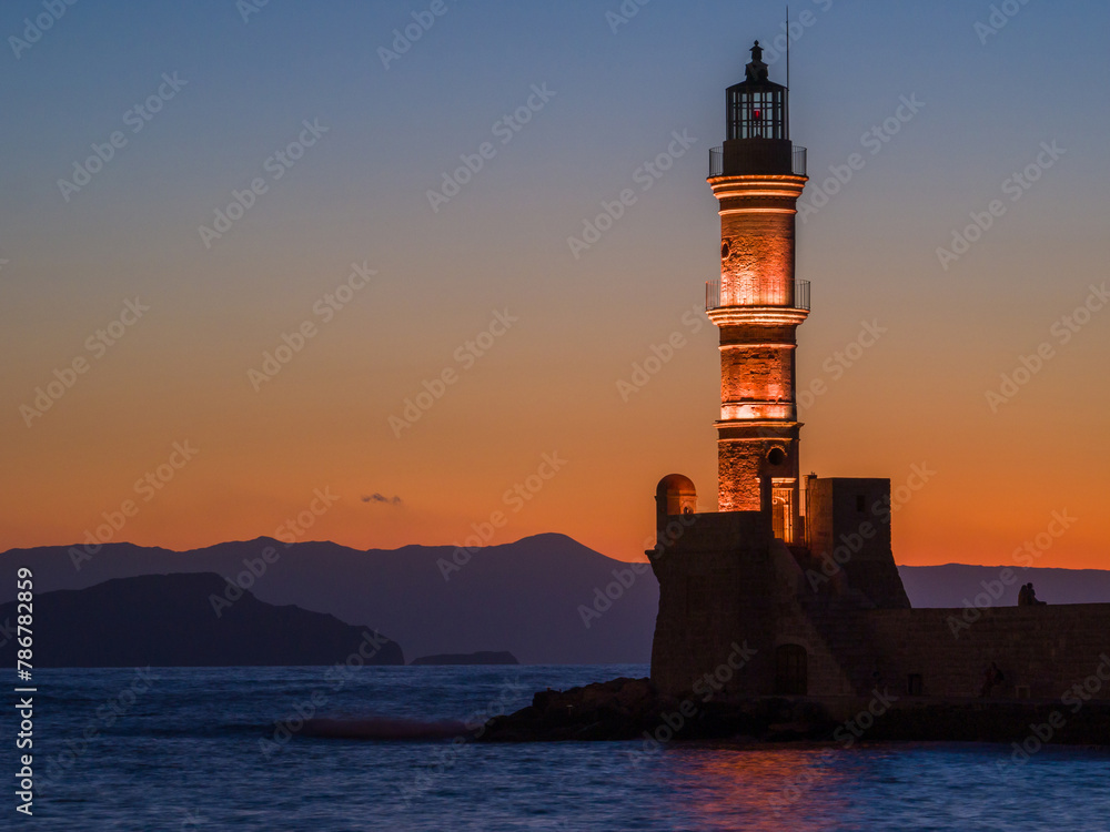 Illuminated old lighthouse in a port town at evening (Chania, Crete, Greece)
