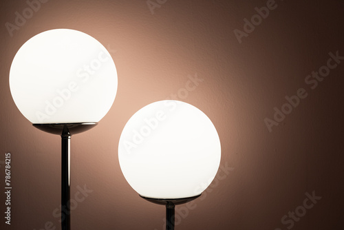 Round lamp, full moon shape with the light bulb inside shining on the wall background in the dark room with copy space.