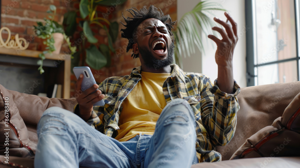 Angry African American man sitting on living room sofa holding phone and screaming while raising one hand, reading bad news Angry African American man sitting on living room sofa holding phone and screaming while raising one hand, reading bad news