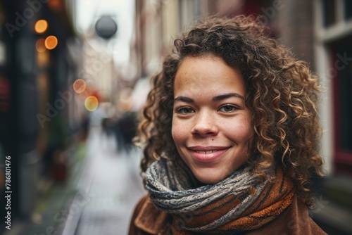 Smiling young woman with curly hair looking at camera in the city © Inigo