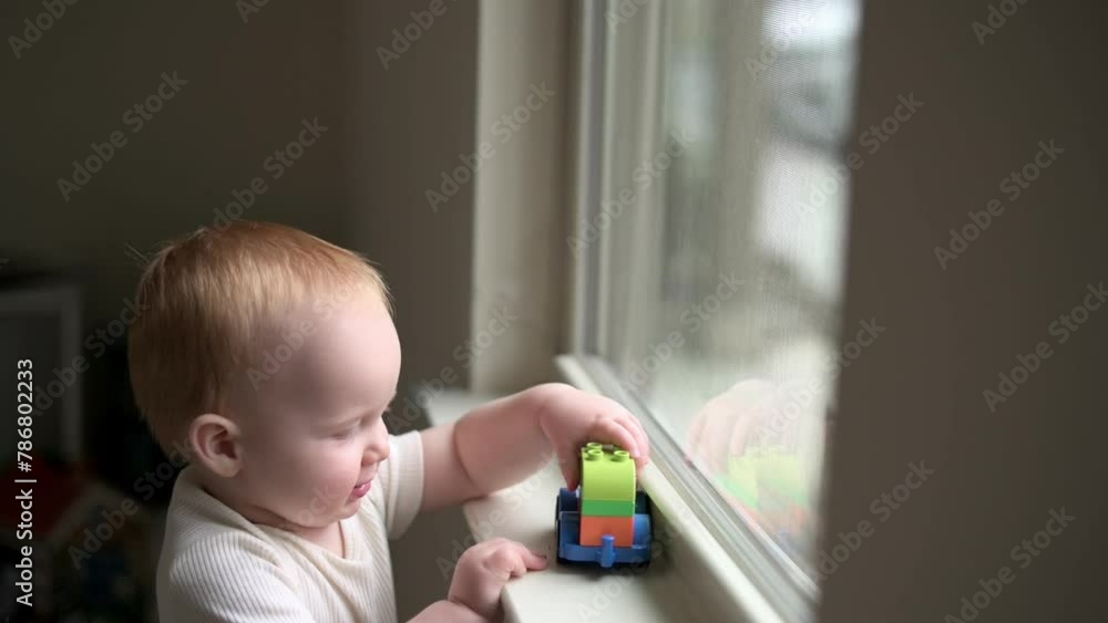one year old toddler, plays with the car toy on the windowsill , playtime, fine motor skills one year old toddler, plays with the car toy on the windowsill , playtime, fine motor skills