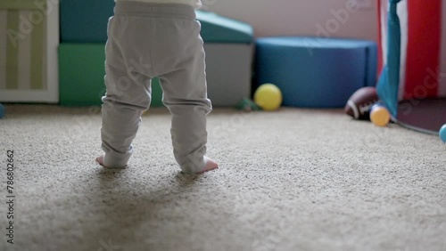 one year old toddler is learning to walk, only legs, no face, walking practice photo
