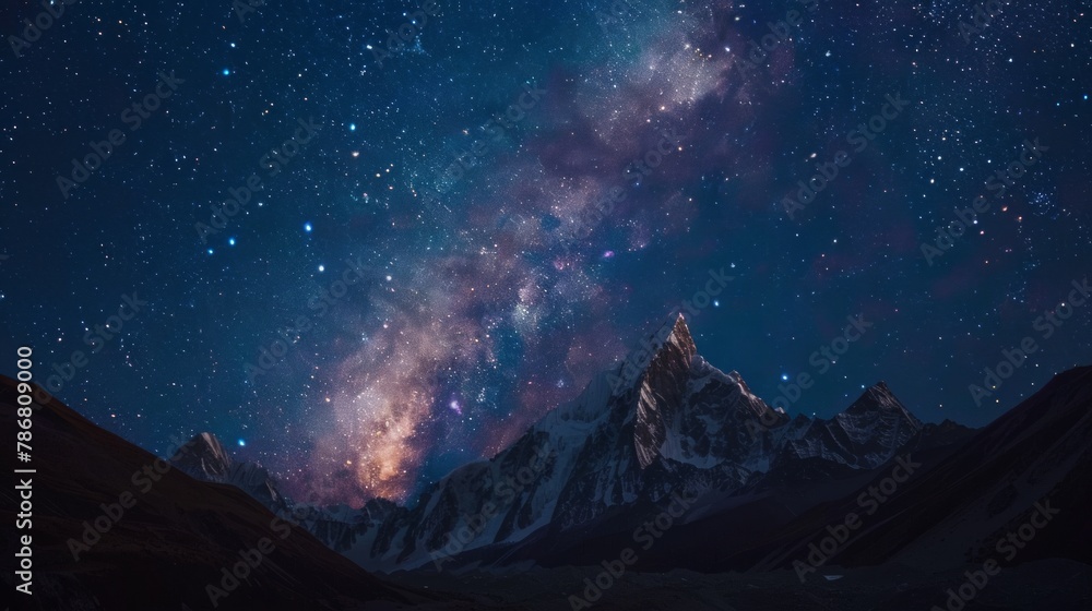 The night sky is filled with stars and a large mountain range in the background