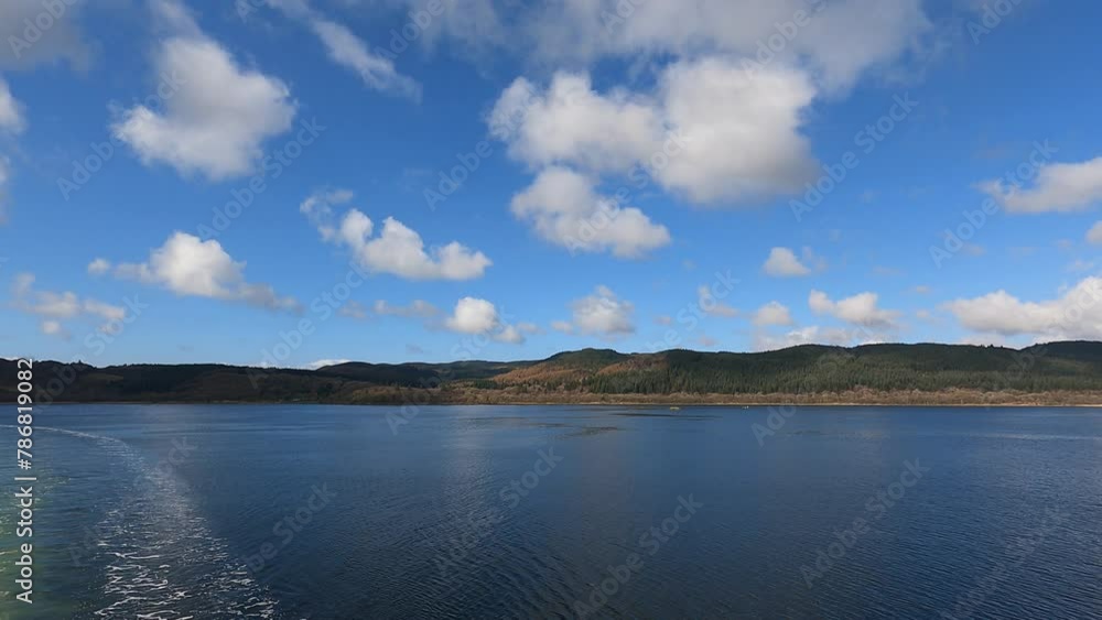 View of the coast of a wide island in Scotland, view from the ferry. Sunny summer day. View of the coast of a wide island in Scotland, view from the ferry. Sunny summer day.