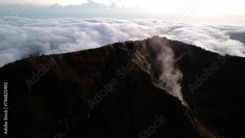 Hikers On Viewpoint Of Mount Batur Volcano With Sea Of Clouds In The Background At Sunrise In Indonesia. - aerial shot photo