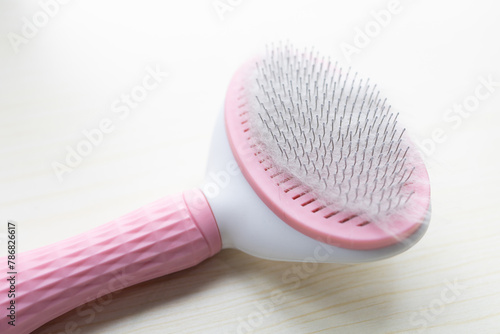 Closeup to a pink grooming cat brush with soft wool