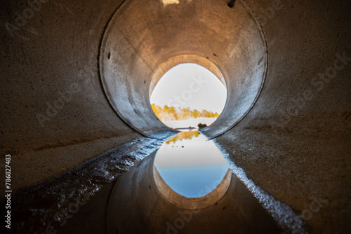 Inside a circular concrete drainage culvert with a trickle of water photo