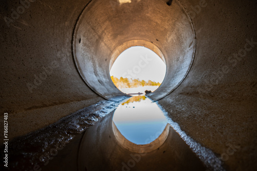 Fotografie Inside a circular concrete drainage culvert with a trickle of water