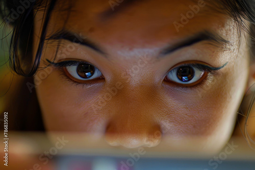 A woman is looking at a screen with her eyes closed