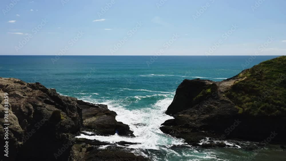As the wave breaks on the rocks water becomes foamy as it rushes into a rocky inlet. As the wave breaks on the rocks water becomes foamy as it rushes into a rocky inlet.