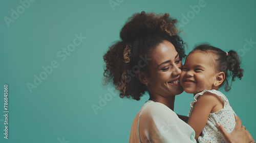 The camera focuses on Happy mother having fun with her daughter on teal color background professional photography.