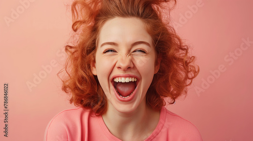 The camera focuses on Overjoyed young redhead woman screaming with joy on pink color background professional photography