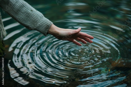 Womans hand touching lake water - concept of cleansing, nature, and sustainability