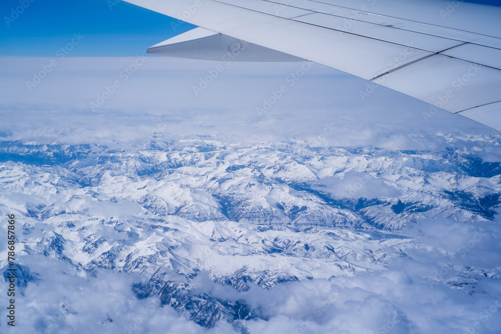 Aerial view through porthole of plane to of snow-covered mountain. Scenic view through aircraft. Airplane. United States Aerial view through porthole of plane to of snow-covered mountain. Scenic view through aircraft. Airplane. United States