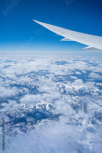 Aerial view through porthole of plane to of snow-covered mountain. Scenic view through aircraft. Airplane. United States