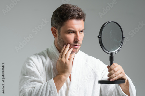 Close-up portrait of perfect brunet man touching chin and skin. Handsome man touching face in gray studio isolated background. Perfect skin. Man cosmetic, skin treatment. Hygiene skin care male face. © Volodymyr