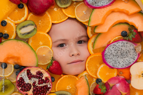 Funny fruits. Kids face with mix of strawberry, blueberry, strawberry, kiwi, dragon fruit, pomegranate, orange and melon. Assorted mix of fruits near child face.