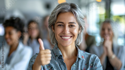 Portrait of beautiful business woman leader with short gray hair happy wearing casual shirt giving thumbs up  group of diverse office workers on blurred background
