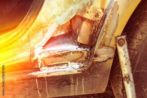 the silver car has a hole in the doorway due to old age and poor care. repair. close-up