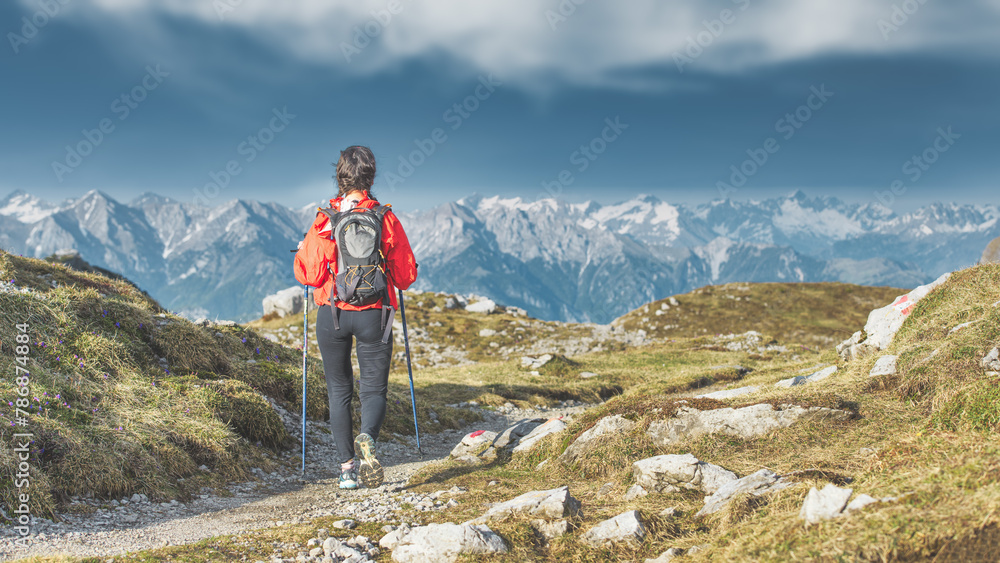 A woman walks on a path in the mountains