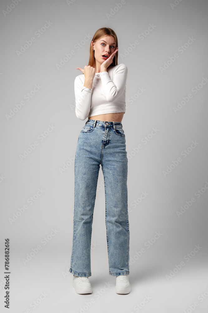 Young Woman Expressing Surprise or Confusion Against a Grey Background Young Woman Expressing Surprise or Confusion Against a Grey Background