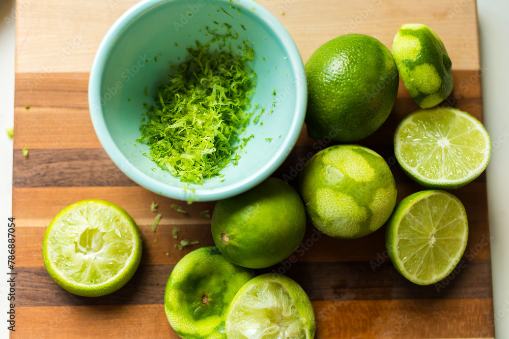 Zested and halved limes on a striped cutting board Zested and halved limes on a striped cutting board