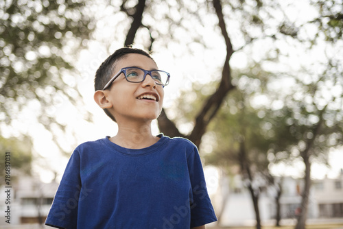 Portrait of a cute boy with glasses laughs at sunset in the park photo