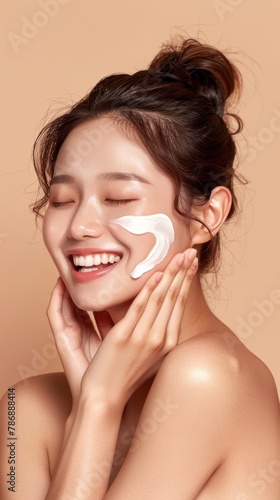 A woman with bare shoulders is applying a white mask to her face