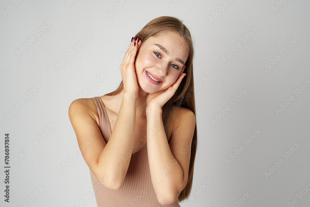 Woman Posing With Hands on Face against gray background Woman Posing With Hands on Face against gray background
